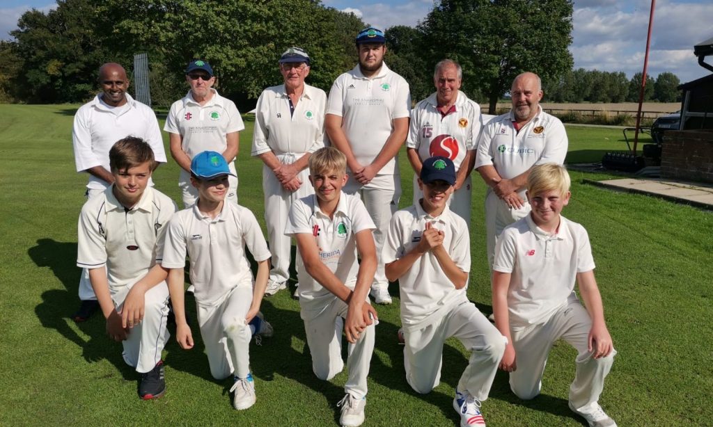 Children and adults posing for a cricket team photo